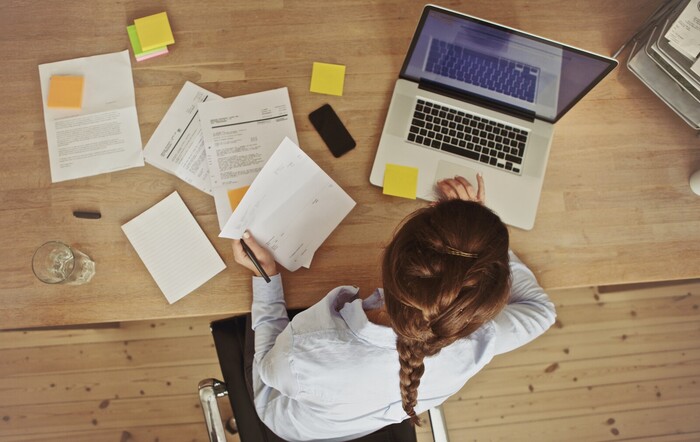 Realtor on a laptop with papers scattered 